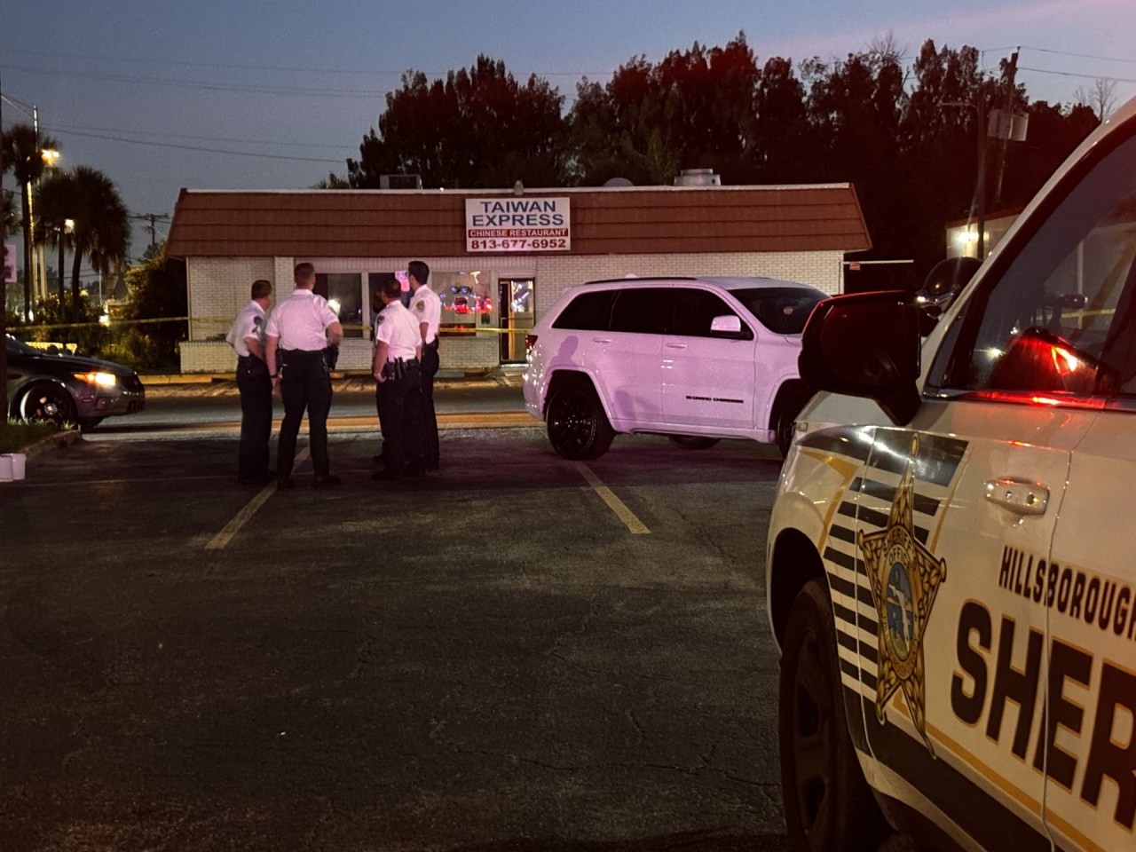 Coche de policía inspeccionando el área de un restaurante por la noche.